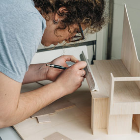 A person designing a wooden prototype of a building