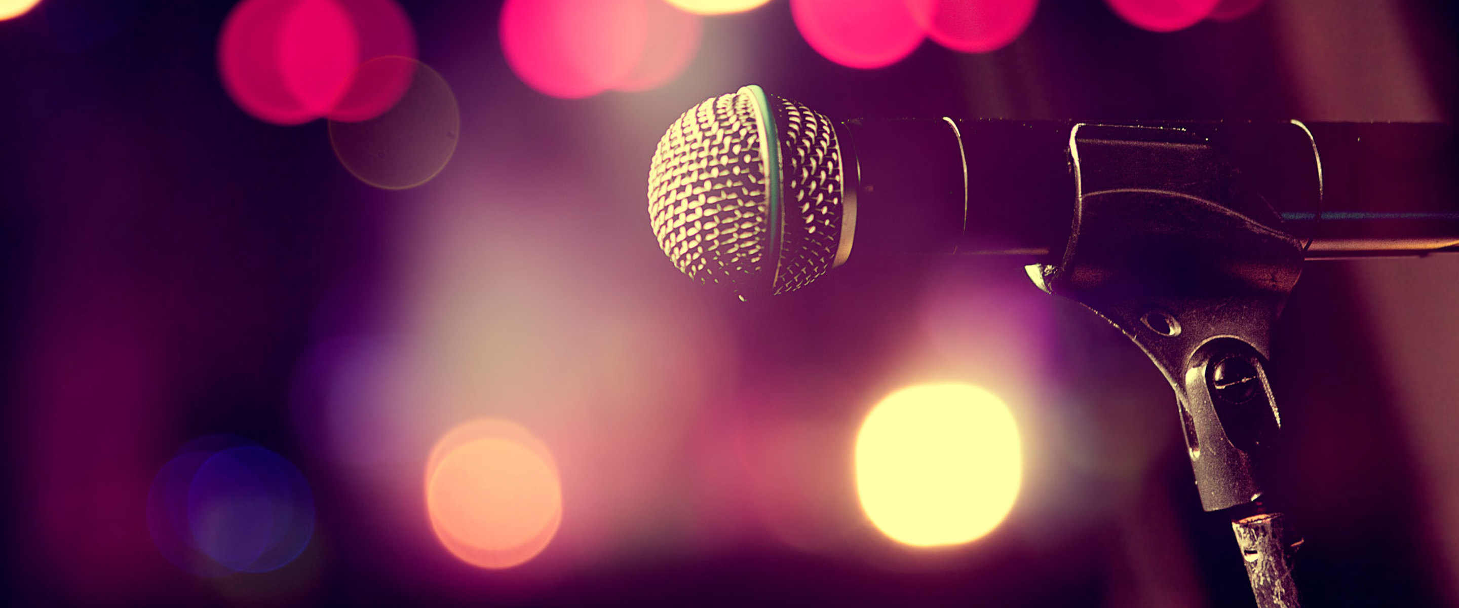 A microphone on stage with stage lights in the background