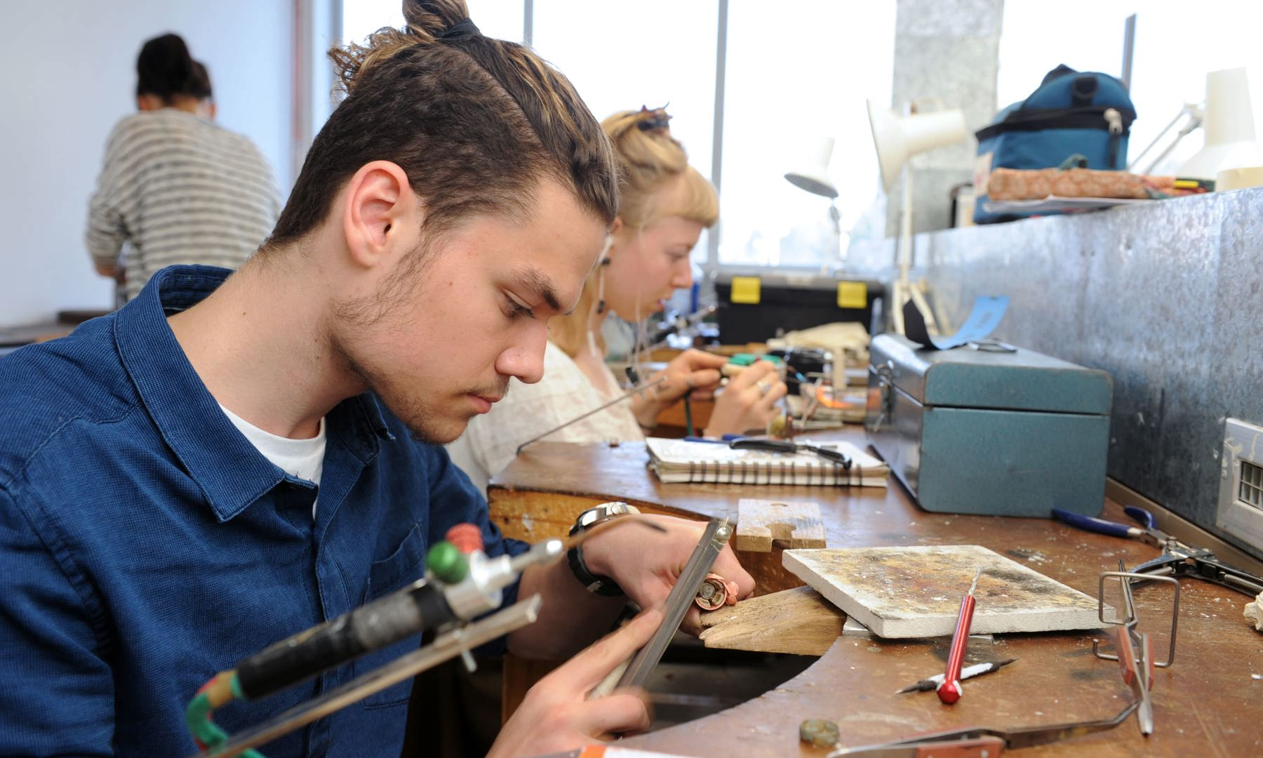Student using a  jeweller's tool at a workshop station