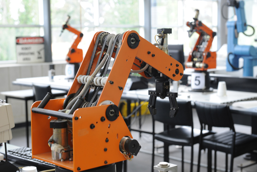 Large orange robotic arm used in manufacturing workshop