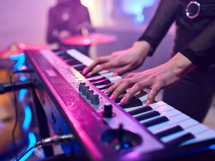 A woman's hands playing the keys of a synthesizer