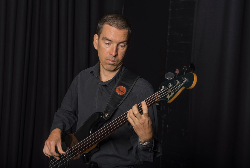 Portrait of Jonathan Diamond playing a bass guitar.