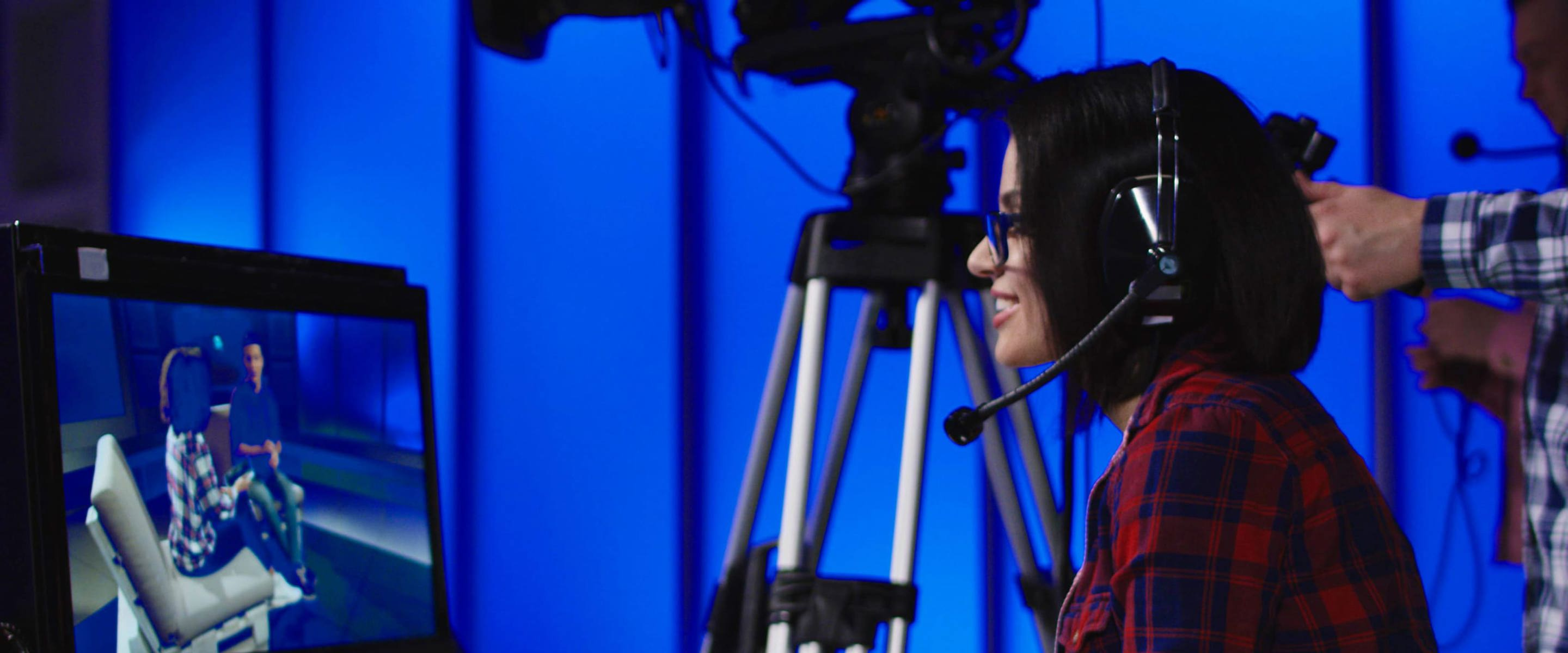 A woman looking into a tv monitor with a camera operator in the background