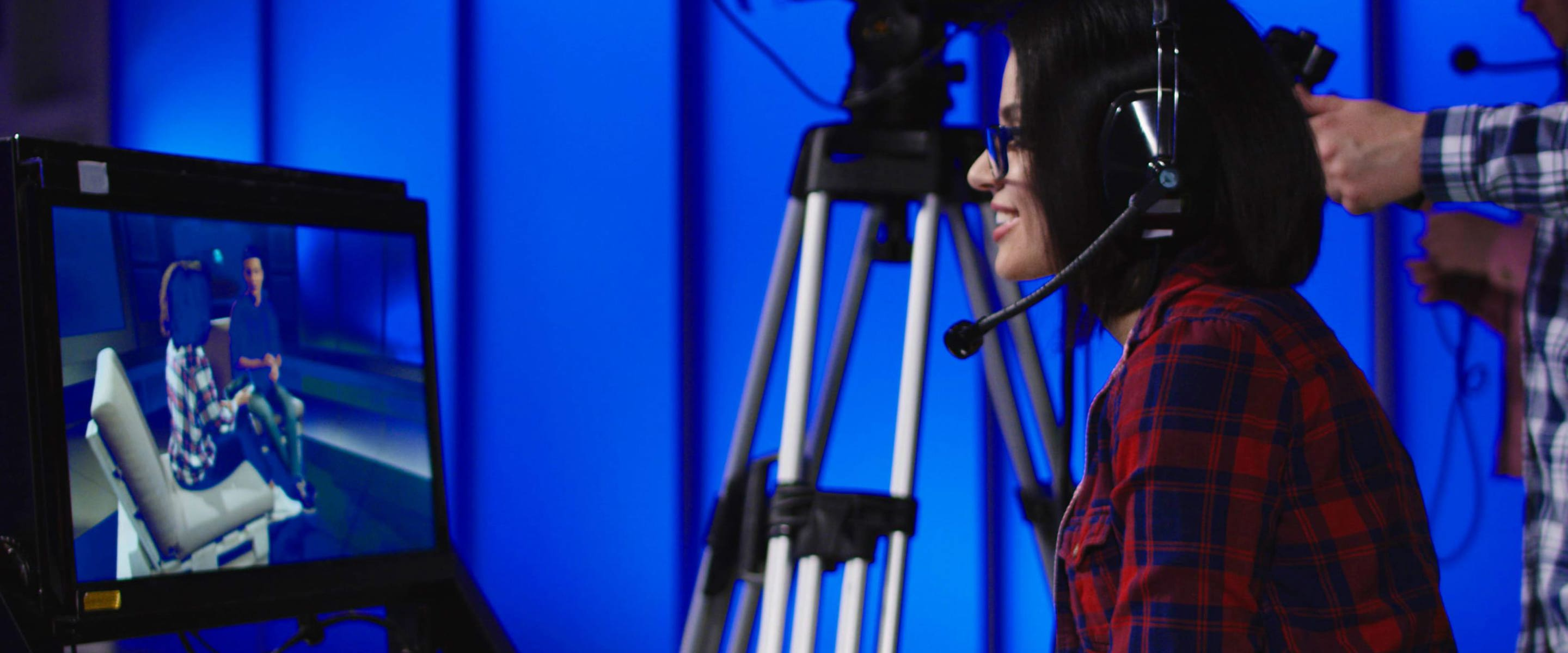A woman looking into a tv monitor with a camera operator in the background