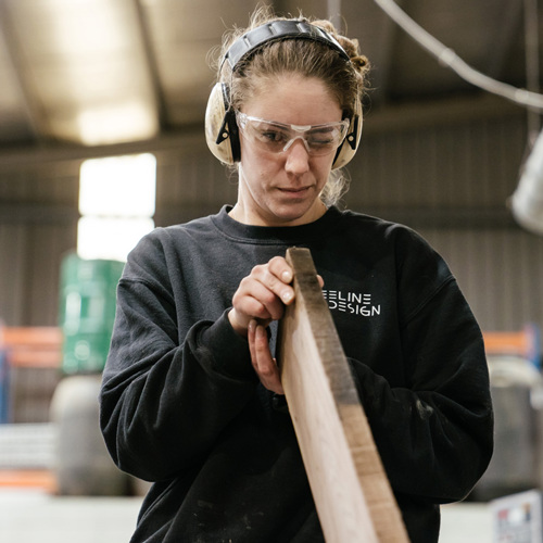 Outstanding Apprentice/Trainee of the Year Jessica Currie inspecting a plank of wood in her Cabinet Making and Joinery class