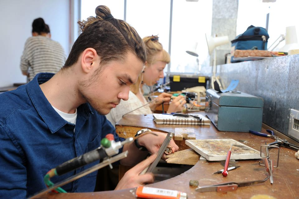 Student using a  jeweller's tool at a workshop station