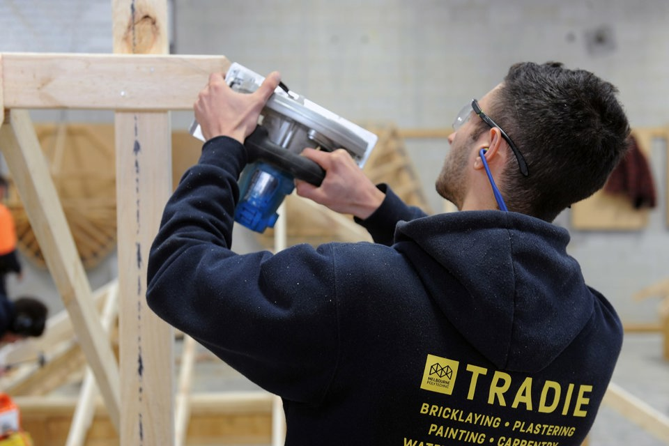 Building Surveying and Construction student with using a hand saw on a timber frame