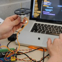 Electronics and Electrical student testing electonic project device with software on laptop