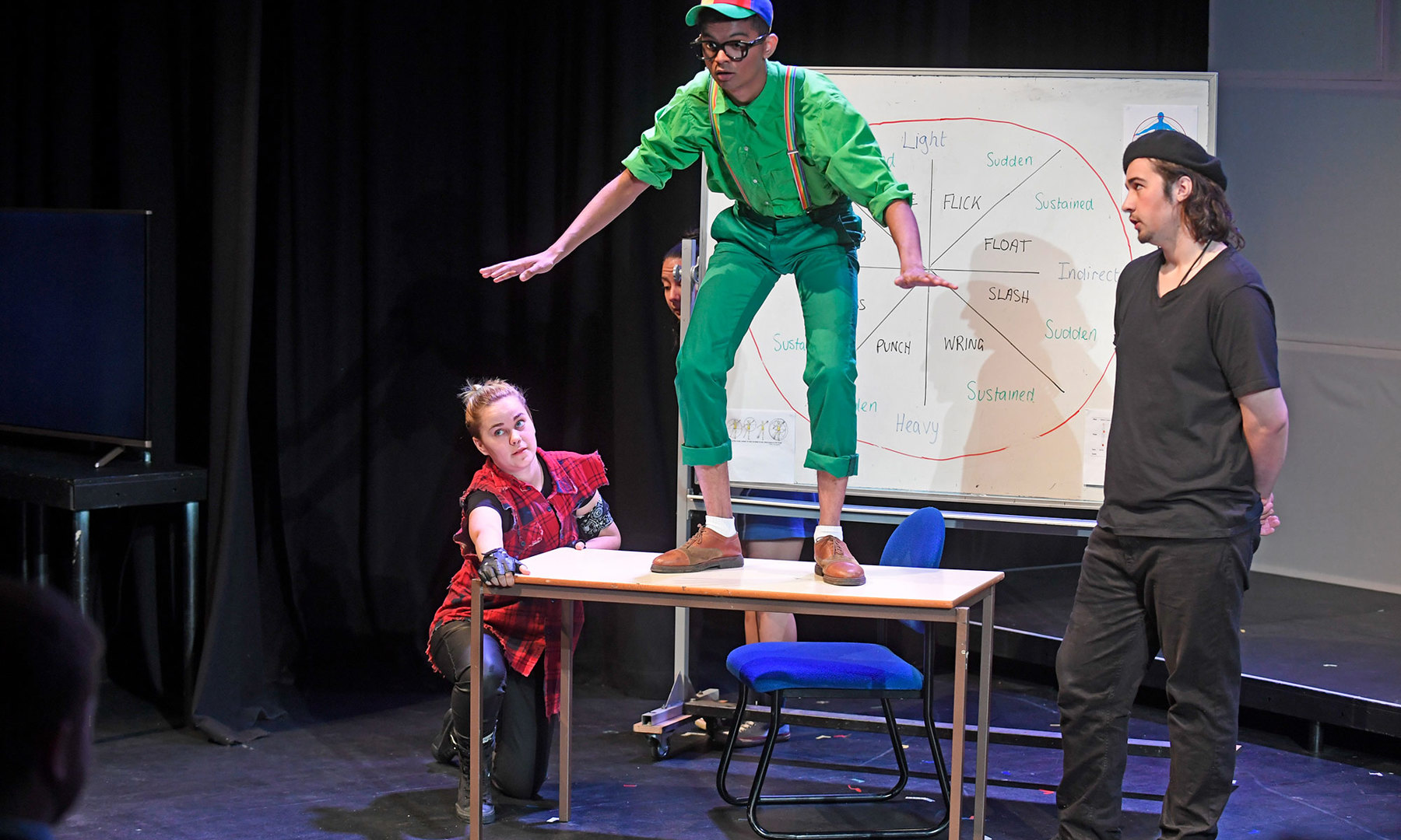 Stage Performance with actor dressed in green balancing on table