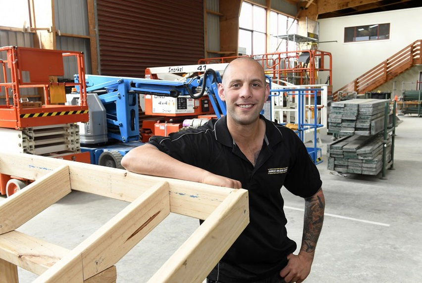 Andrew Guglielmino leaning on a wooden frame in purpose built practical industry enviornment shed on campus