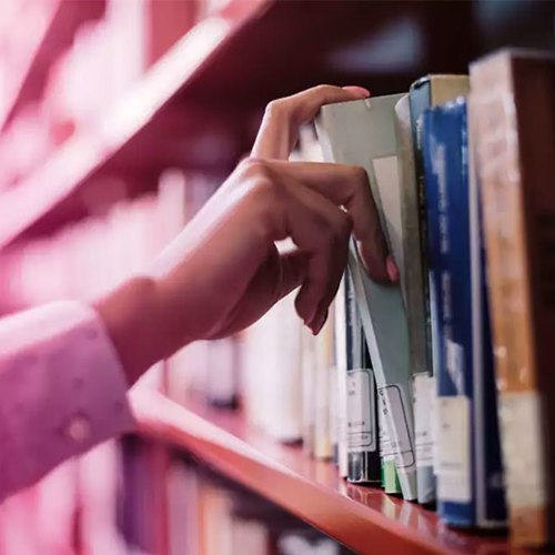 Woman's hands reaching for a book from the library shelf
