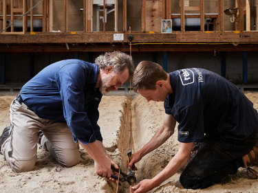 Two men actively working together on a construction site, surrounded by tools and building materials.