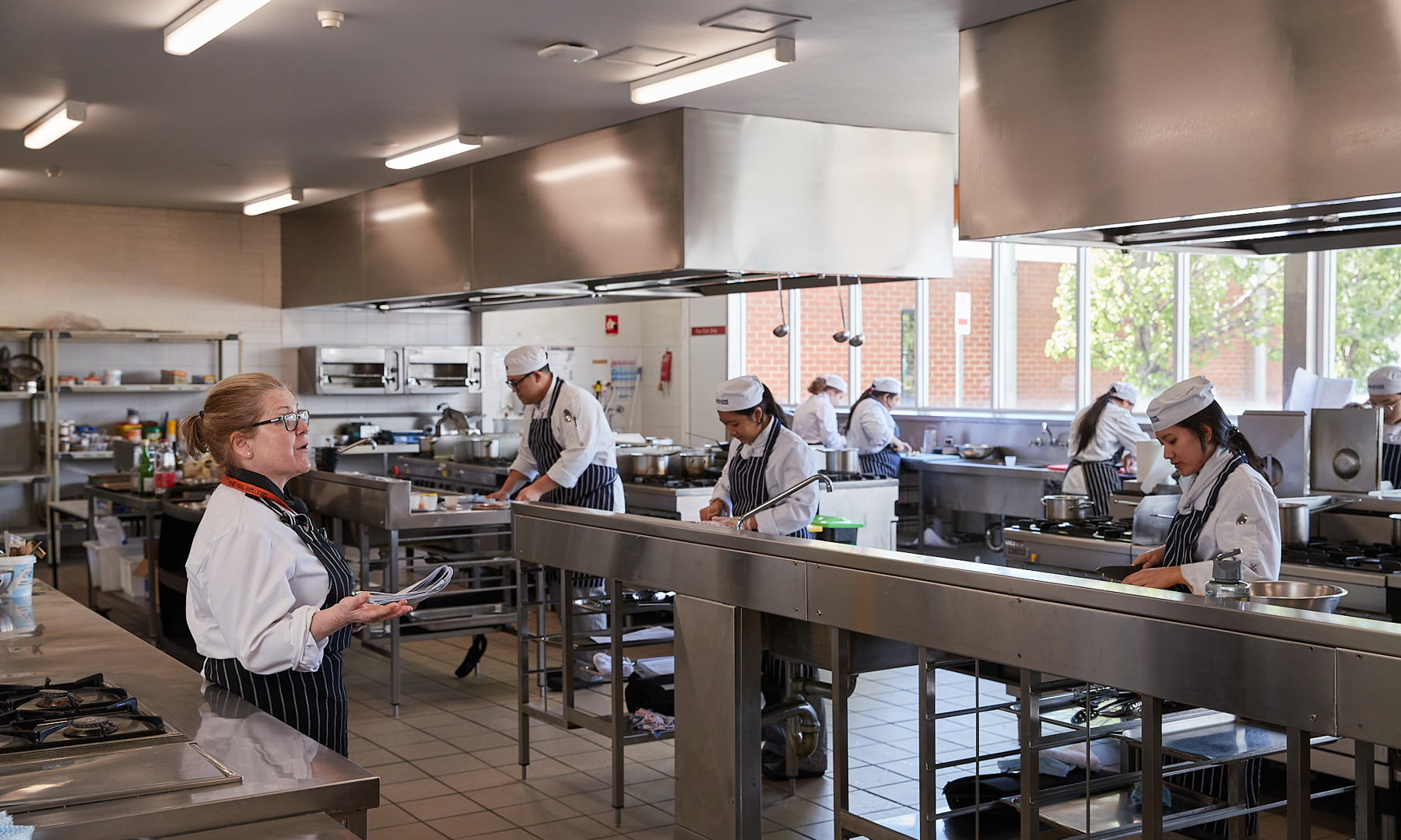 Preston hospitality cookery students preparing food in kitchen facility while under instruction.