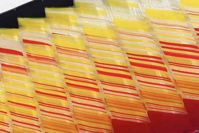 Close-up image of red, orange, and yellow, and black stained glass artwork that resembles a staircase pattern on a white background.