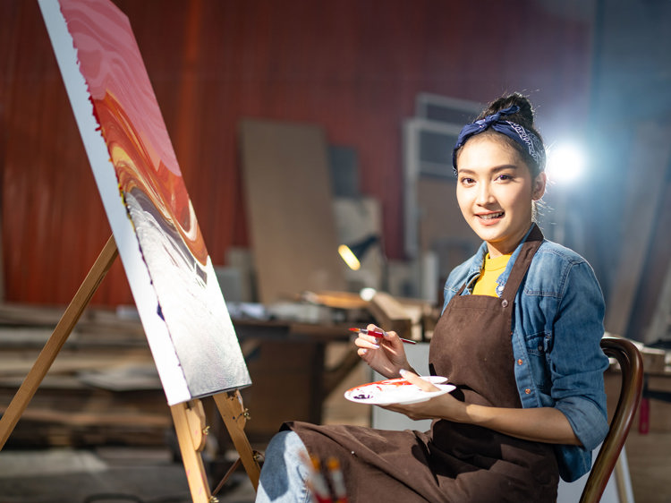 A woman painting on a canvas with a paintbrush