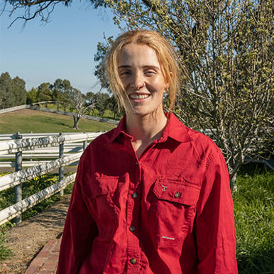 A woman in a red shirt standing outdoors smiling 