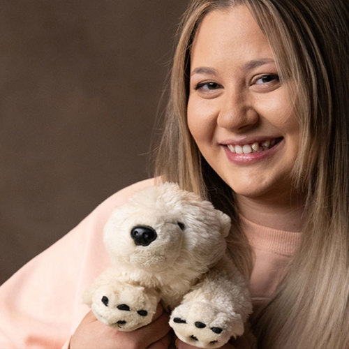  A smiling woman with a stuffed animal in her hand smiling