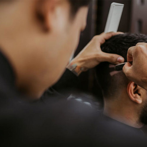 Male barber styling a clients hair in the salon