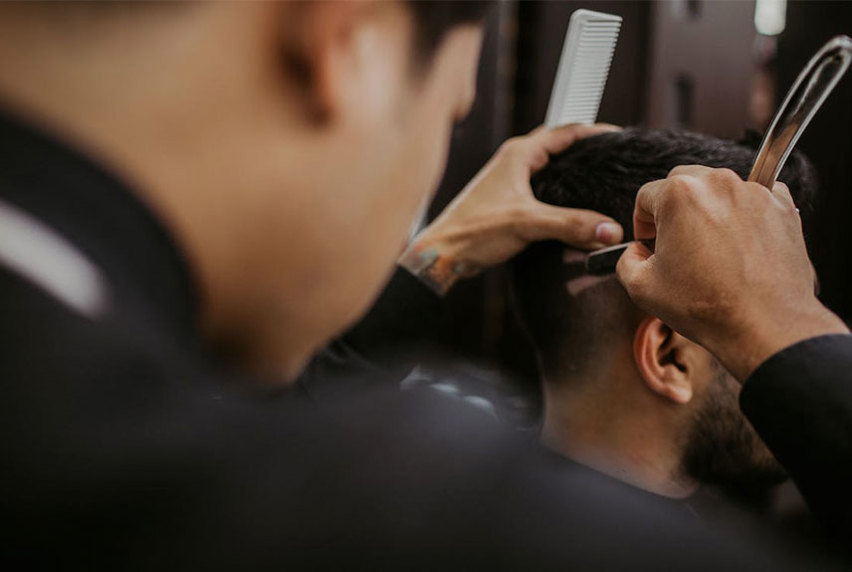 Male barber styling a clients hair in the salon