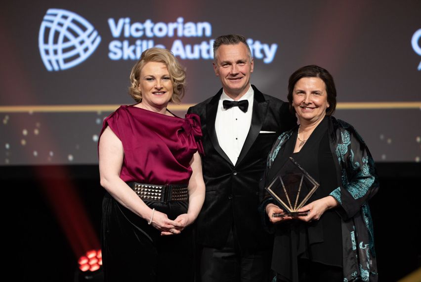 Melbourne Polytechnic Chief Executive, Frances Coppolillo, and Executive Director, Cathy Frazer, stand on stage after accepting the award for Inclusive Training Provider of the Year 2023.