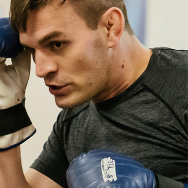 Image of a man wearing blue and white boxing gloves as he trains 