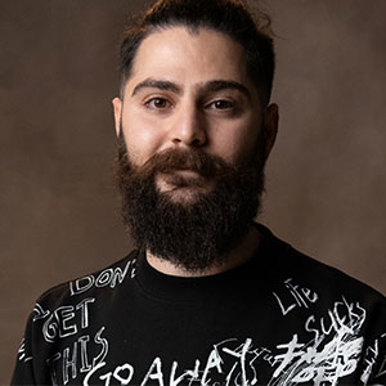 A bearded man wearing a black shirt with text