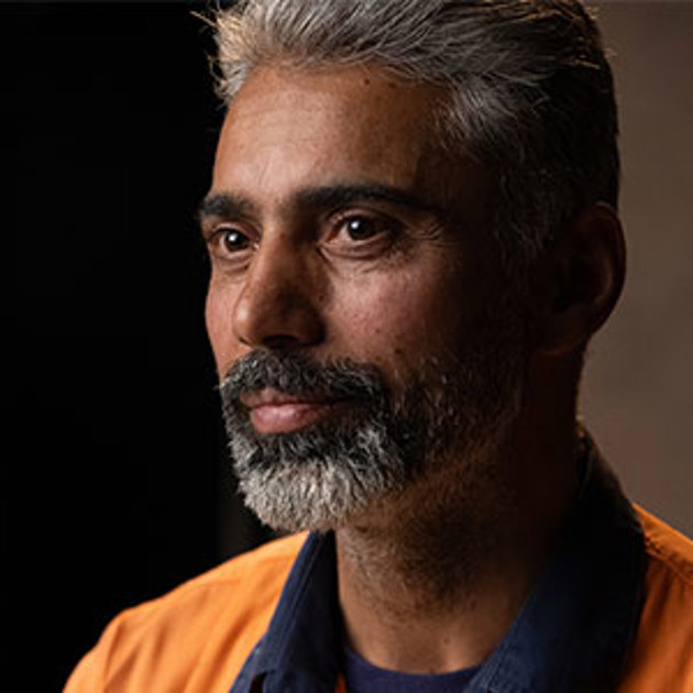 A gentleman with grey hair and a beard dressed in a high vis orange shirt